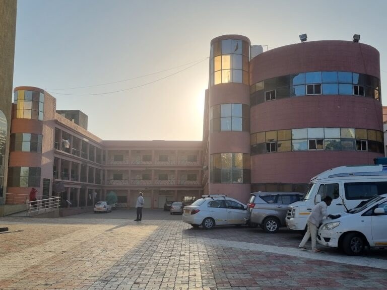 Courtyard of Maharashtra Bhuvan with parked vehicles and rose-coloured towers