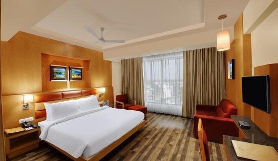 Triple bed room with king-sized bed, red couch and smart TV at Maharashtra Bhuvan Palitana