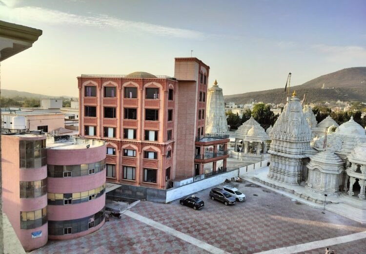 Maharashtra Bhuvan building next to the white marble Jain temples of Palitana at golden hour